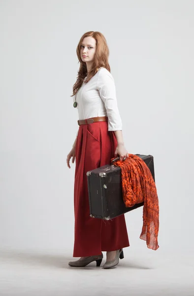 Donna in gonna rossa vintage con una valigia — Foto Stock