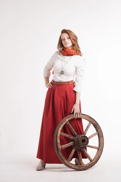 Женщина в длинной красной юбке, стоящая возле колеса тележки — стоковое фото