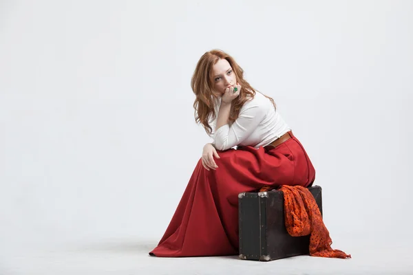 Donna seduta su valigia, isolata, sfondo bianco — Foto Stock