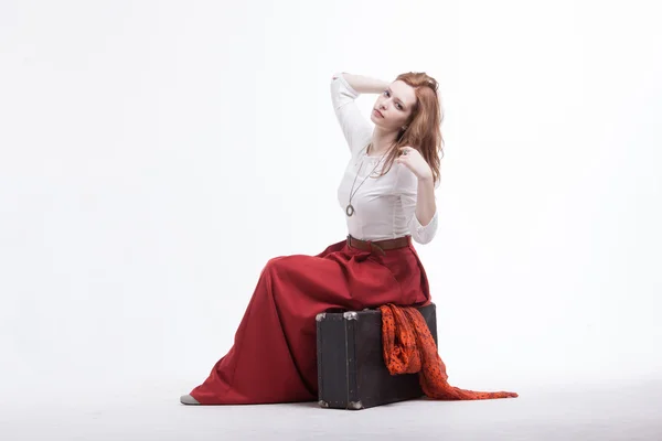 Femme assise sur une valise, isolée, fond blanc — Photo