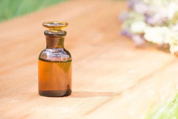 Aceite esencial en botella pequeña y hierbas medicinales de las flores — Foto de Stock