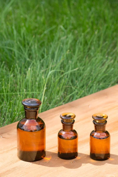 Piccole bottiglie marroni su tavola booden ed erba — Foto Stock