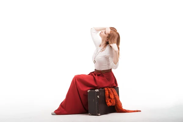 Femme assise sur une valise, isolée, fond blanc — Photo