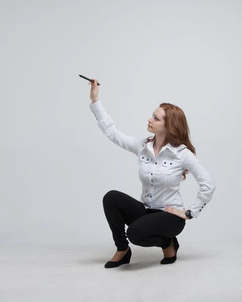 Jonge vrouw met pen op een grijze achtergrond — Stockfoto