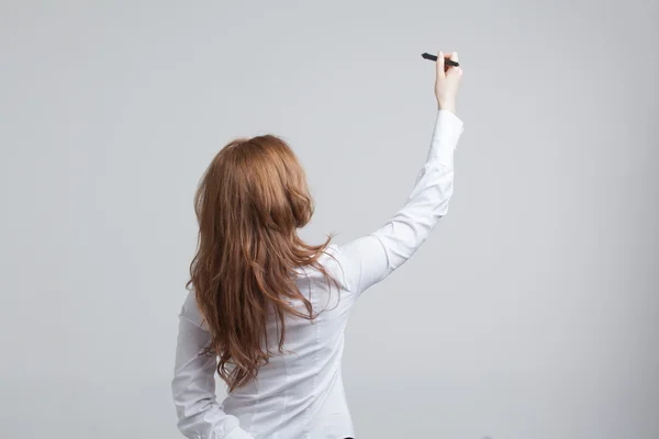 Jovem mulher com caneta sobre fundo cinza — Fotografia de Stock