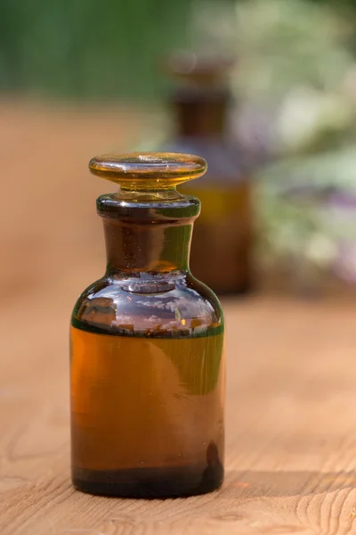 Aceite esencial en botella pequeña y hierbas medicinales de las flores — Foto de Stock