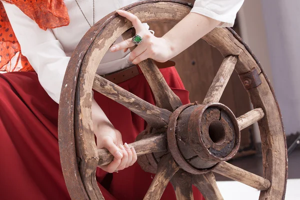 Old wooden wheel an womans hands with a ring — Stock Photo, Image