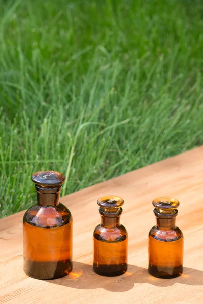 Pequeñas botellas marrones en booden tablero y hierba — Foto de Stock