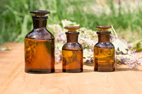 Aceite esencial en botella pequeña y hierbas medicinales de las flores — Foto de Stock