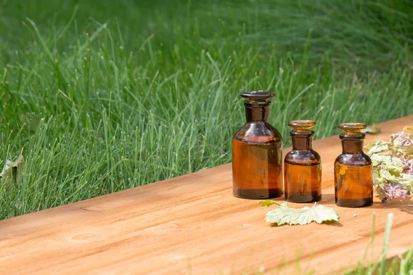 Aceite esencial en botella pequeña y hierbas medicinales de las flores — Foto de Stock