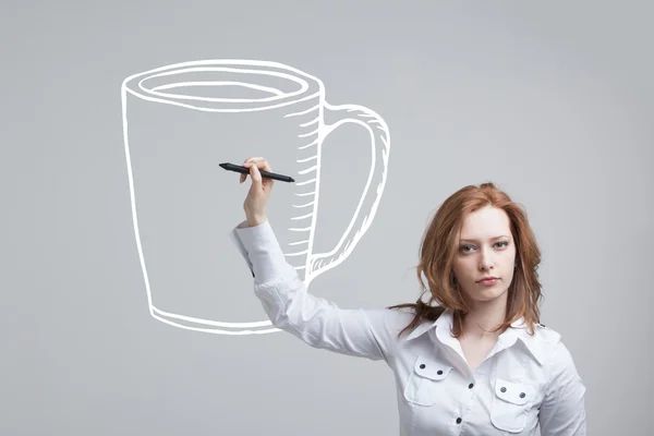 Jovem mulher desenha uma xícara de café em fundo cinza — Fotografia de Stock