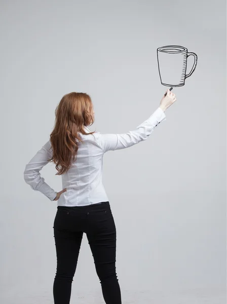 Genç kadın bir fincan kahve gri arka plan üzerine çizer. — Stok fotoğraf
