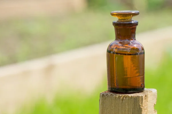 Pequeña botella marrón y hierba — Foto de Stock
