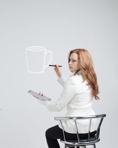 Junge Frau zeichnet eine Tasse Kaffee auf grauem Hintergrund — Stockfoto