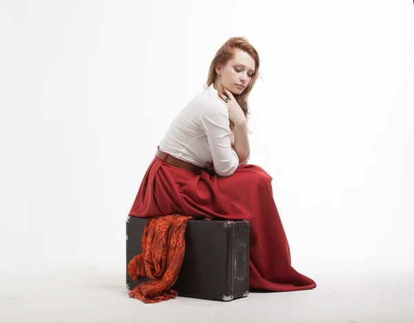 Femme assise sur une valise, isolée, fond blanc — Photo