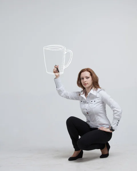 Young woman draws a Cup of coffee on grey background — Stock Photo, Image