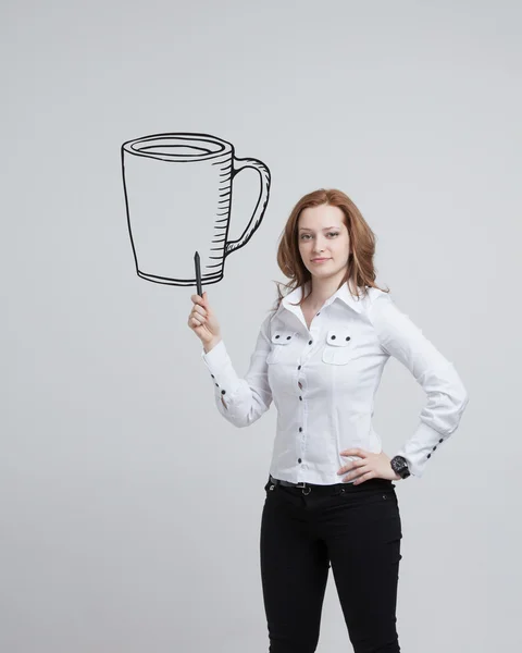 Joven mujer dibuja una taza de café sobre fondo gris — Foto de Stock
