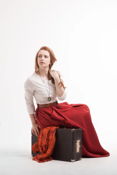 Femme assise sur une valise, isolée, fond blanc — Photo