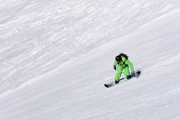 Idąc w dół stoku w ośrodku narciarskim snowboardzista. — Zdjęcie stockowe