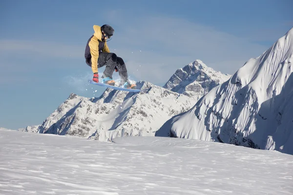 Um snowboarder voador nas montanhas. Desporto extremo. — Fotografia de Stock