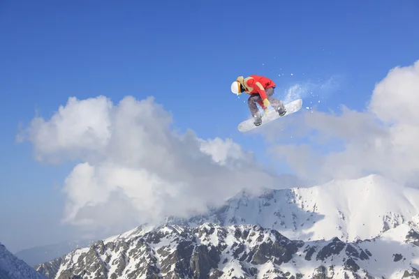 Um snowboarder voador nas montanhas. Desporto extremo. — Fotografia de Stock