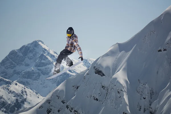 Um snowboarder voador nas montanhas. Desporto extremo. — Fotografia de Stock