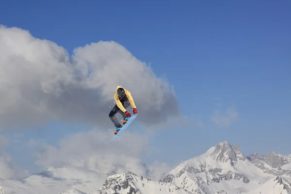 Um snowboarder voador nas montanhas. Desporto extremo. — Fotografia de Stock