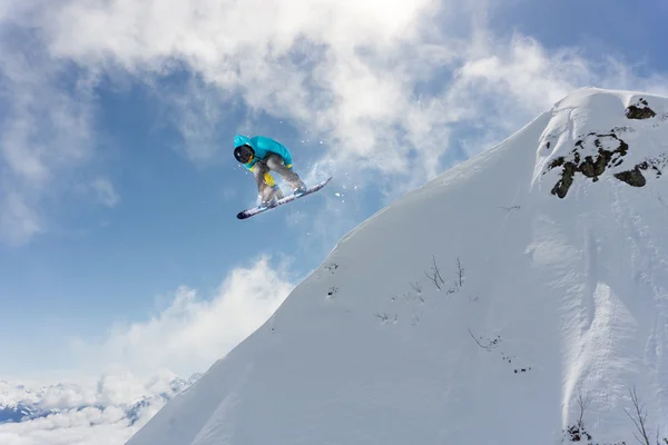 Um snowboarder voador nas montanhas. Desporto extremo. — Fotografia de Stock