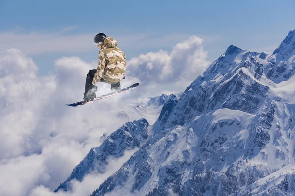 Um snowboarder voador nas montanhas. Desporto extremo. — Fotografia de Stock