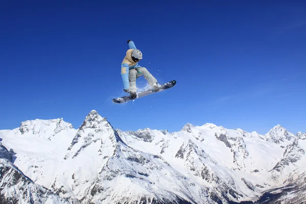 Um snowboarder voador nas montanhas. Desporto extremo. — Fotografia de Stock