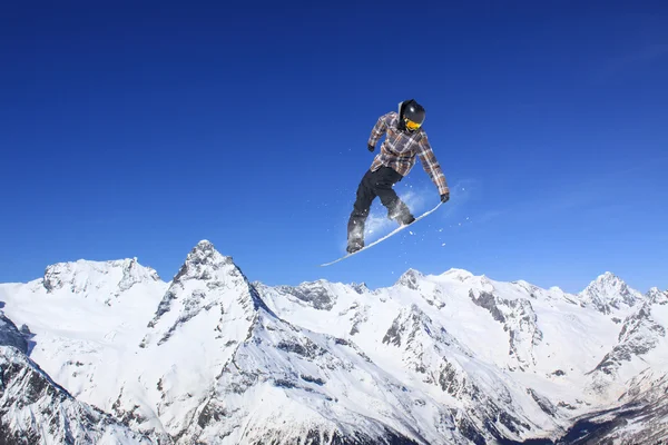 Repülő snowboardos a hegyekben. Extrém sport. — Stock Fotó