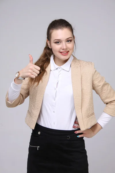 Pulgar hacia arriba. Mujer de negocios sobre fondo gris. Modelo femenino . — Foto de Stock