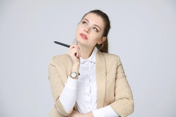 Młody biznes kobieta myśli, w ręku trzyma długopis — Zdjęcie stockowe