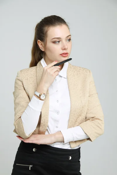 Joven mujer de negocios pensando, sosteniendo la pluma en la mano — Foto de Stock