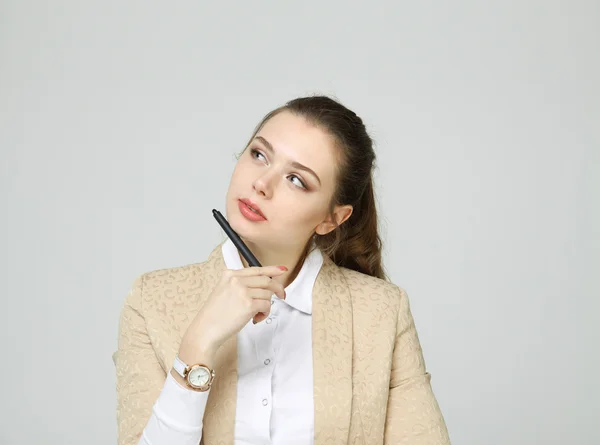 Junge Geschäftsfrau denkt und hält Stift in der Hand — Stockfoto