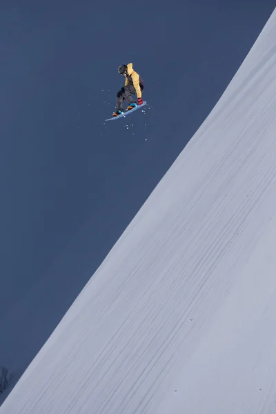 Um snowboarder voador nas montanhas. Desporto extremo. — Fotografia de Stock