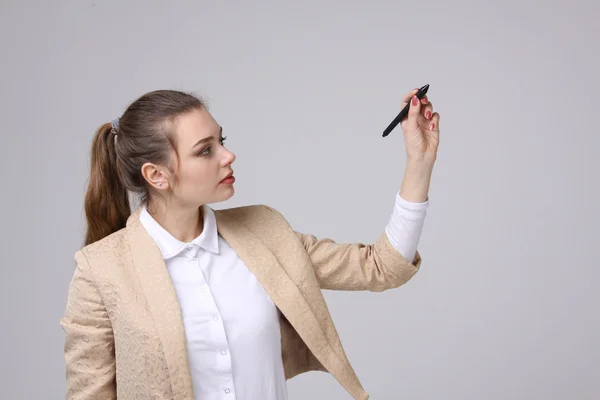 Mladá žena s perem na šedém pozadí — Stock fotografie