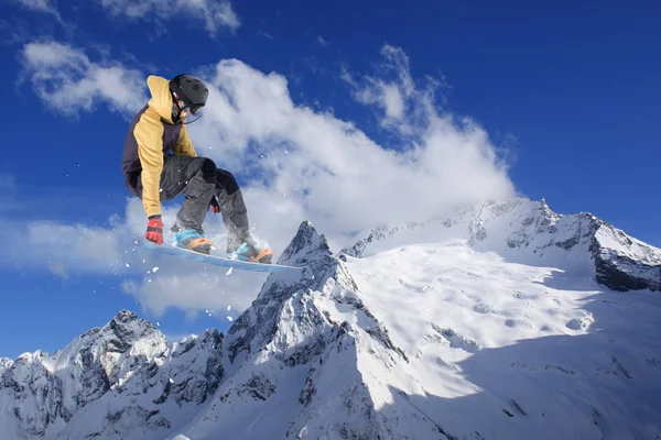 Um snowboarder voador nas montanhas. Desporto extremo. — Fotografia de Stock