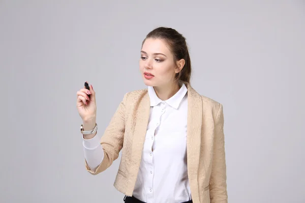 Junge Frau mit Stift auf grauem Hintergrund — Stockfoto