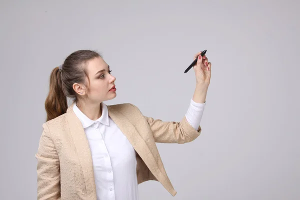 Young woman with pen on grey background — Stock Photo, Image