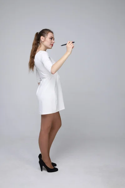 Mladá žena s perem na šedém pozadí — Stock fotografie