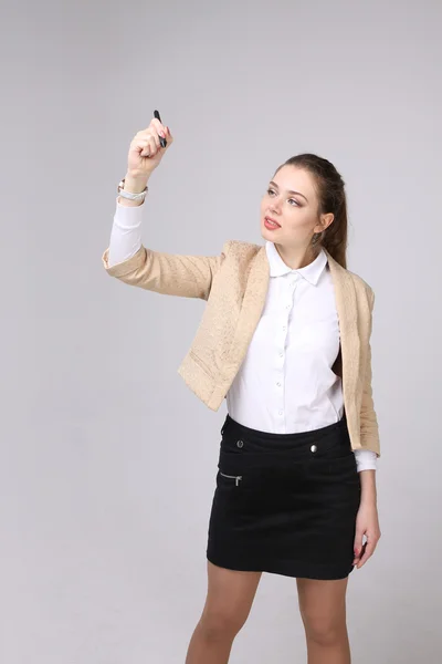 Jonge vrouw met pen op een grijze achtergrond — Stockfoto