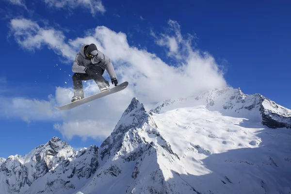 Um snowboarder voador nas montanhas. Desporto extremo. — Fotografia de Stock