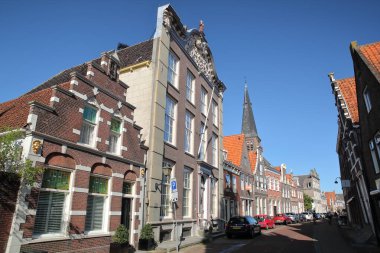 MONNICKENDAM, NETHERLANDS - 15 Eylül 2020: Arka planda Nicolaas ve Anthonius kiliselerinin çan kulesi ve Noordeinde caddesi boyunca yer alan tarihi ev cepheleri