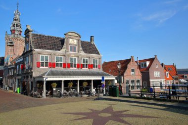 Arka planda Speeltoren (Carillon) kulesi ve kulesi bulunan Kuzey Hollanda, Monnickendam limanında bulunan tarihi ev cepheleri