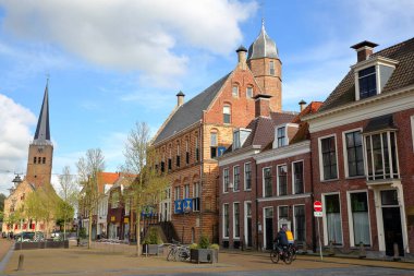 FRANEKER, NETHERLANDS - MAY 16, 2021: The medieval facade of Museum Martena and the clock tower of Martinikerk (St Martin church) on the right, viewed from Voorstraat street in Franeker, Friesland