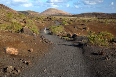 Lanzarote, Kanarya Adaları, İspanya 'daki Caldera Colorada çevresinde kırmızı ve kayalık araziler ve volkanlarla çevrili popüler yürüyüşün yer aldığı renkli bir manzara.