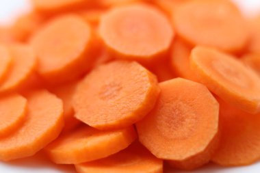 Makro yakın plan kesilmiş taze havuçlar parlak turuncu renkler ve doğal dokuları gösteriyor. Yumuşak odak ve sığ alan derinliği, beslenme, yemek pişirme ve vejetaryen temaları için uygun temiz, iştah açıcı ve sağlıklı bir gıda arka planı oluşturur..