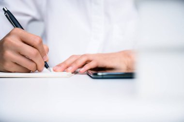 İnsanlar deftere yazı yazıp ahşap masa üzerinde kağıt üzerinde çalışıyorlar..