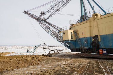 Yürüyen bir kılavuz kazıcı kilden bir çukurda aşırı yük taşır. Zaporizhia bölgesi, Ukrayna. Ocak 2015